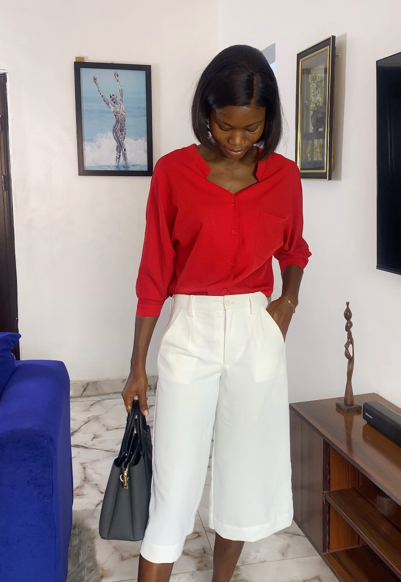 Woman in a red top and white skirt standing in a living room. Women's tailored jorts. Business casual shorts for women, Knee-length women's shorts, Tailored women's shorts