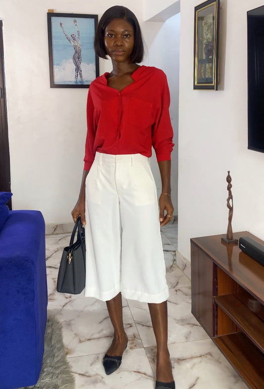 Woman in a red top and white skirt standing in a living room. Women's tailored jorts. Business casual shorts for women, Knee-length women's shorts, Tailored women's shorts